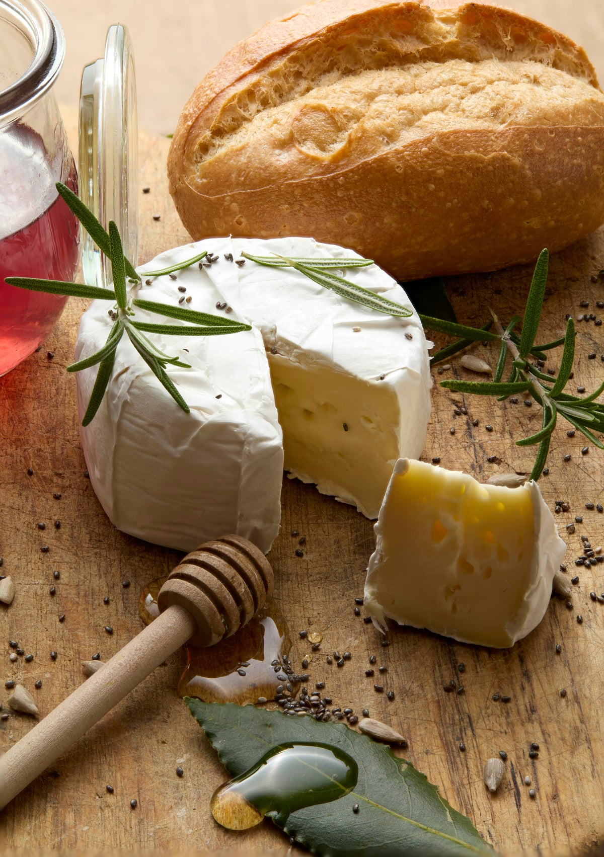 Camembert nappé de miel avec cuillère à miel et baguette sur une planche en bois